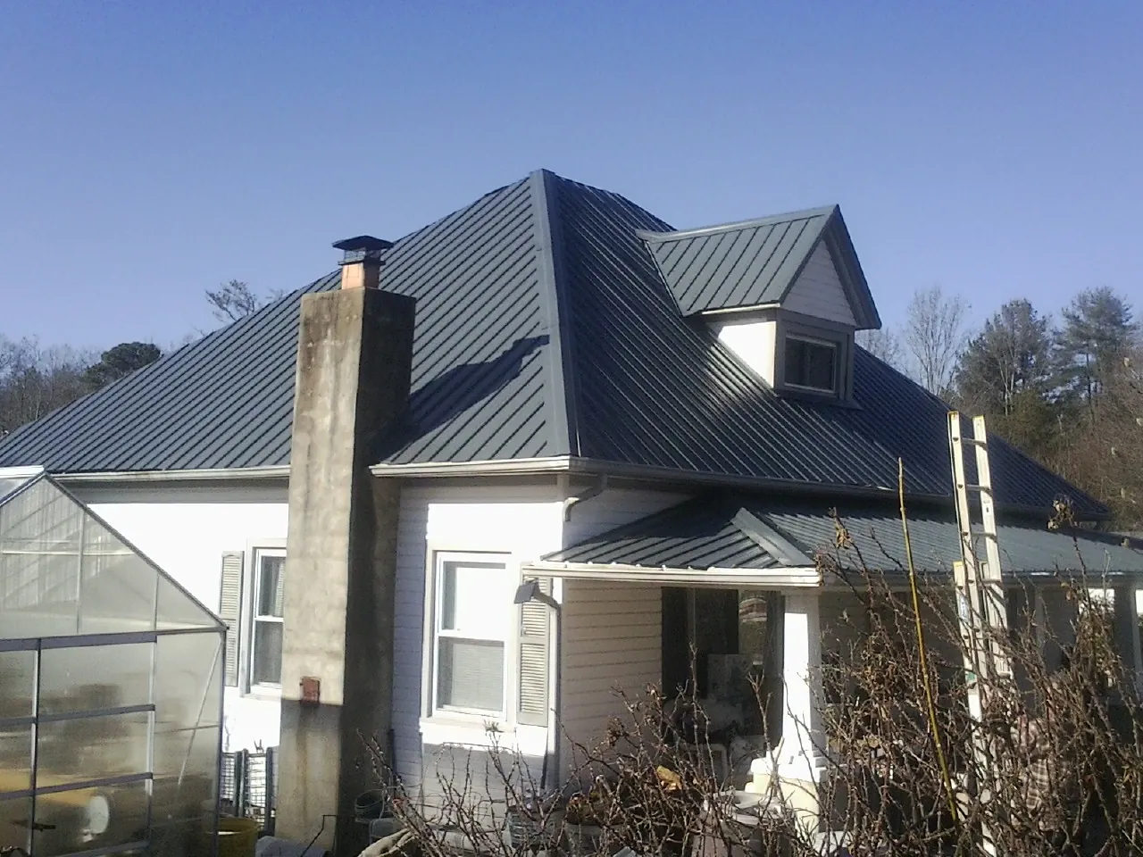 Dark blue standing seam metal roof on a white farmhouse with dormer — Slate & Tile Roof Repair by Roofing Brothers in Ithaca